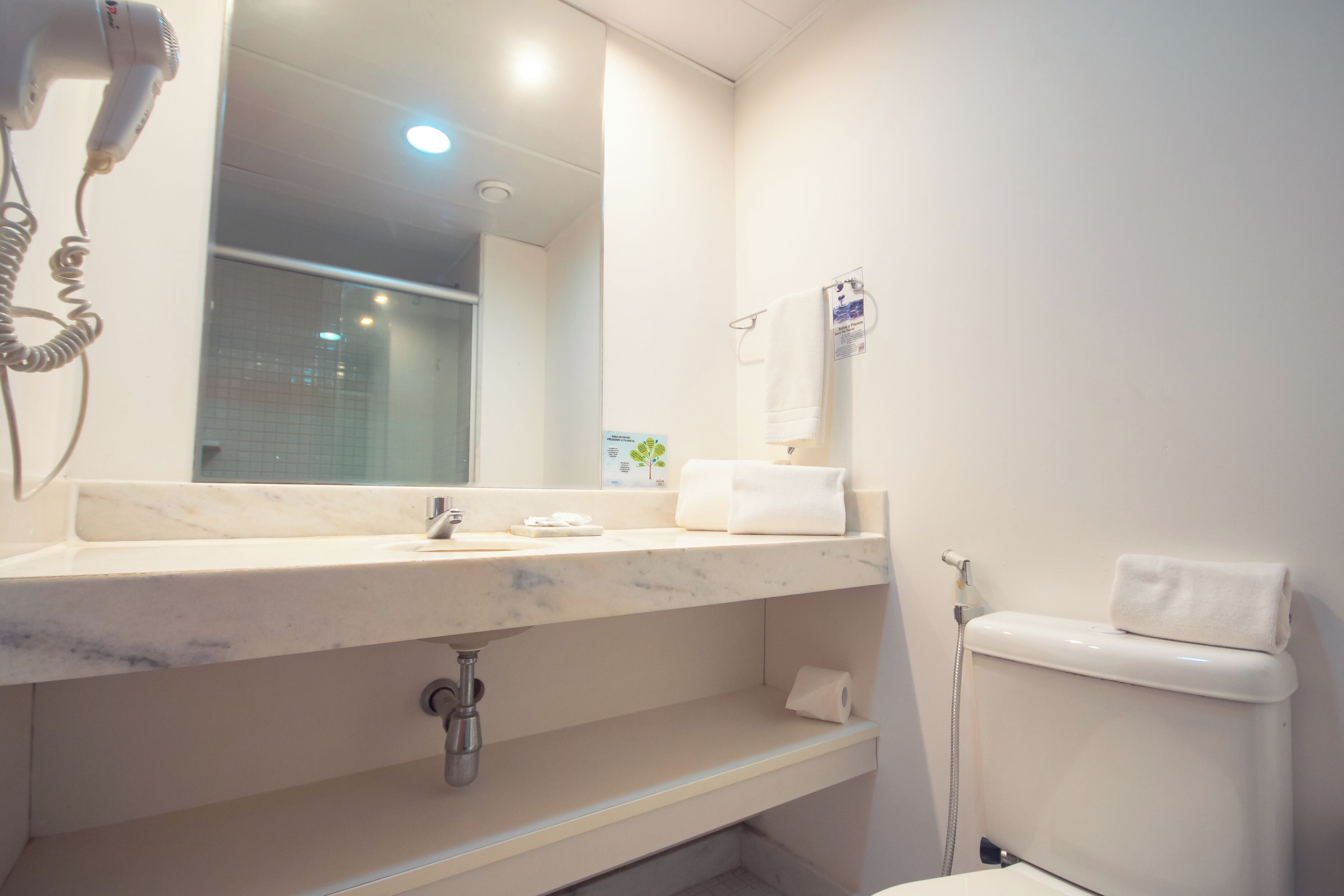 A bathroom with a marble sink, a hairdryer, a towel rack, and a toilet.