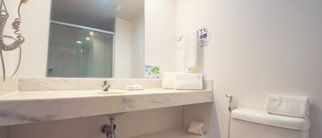 A bathroom with a marble sink, a hairdryer, a towel rack, and a toilet.