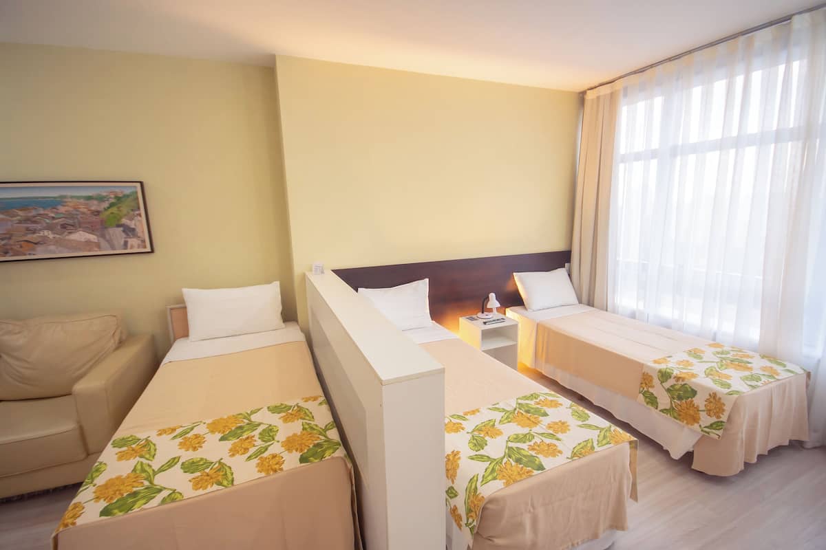 Een hotelkamer met twee enkele bedden, een bank, een nachtkastje en een schilderij aan de muur.