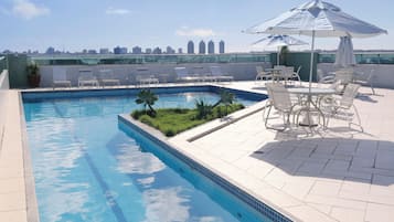 Een buitenzwembad, parasols bij het zwembad en ligstoelen