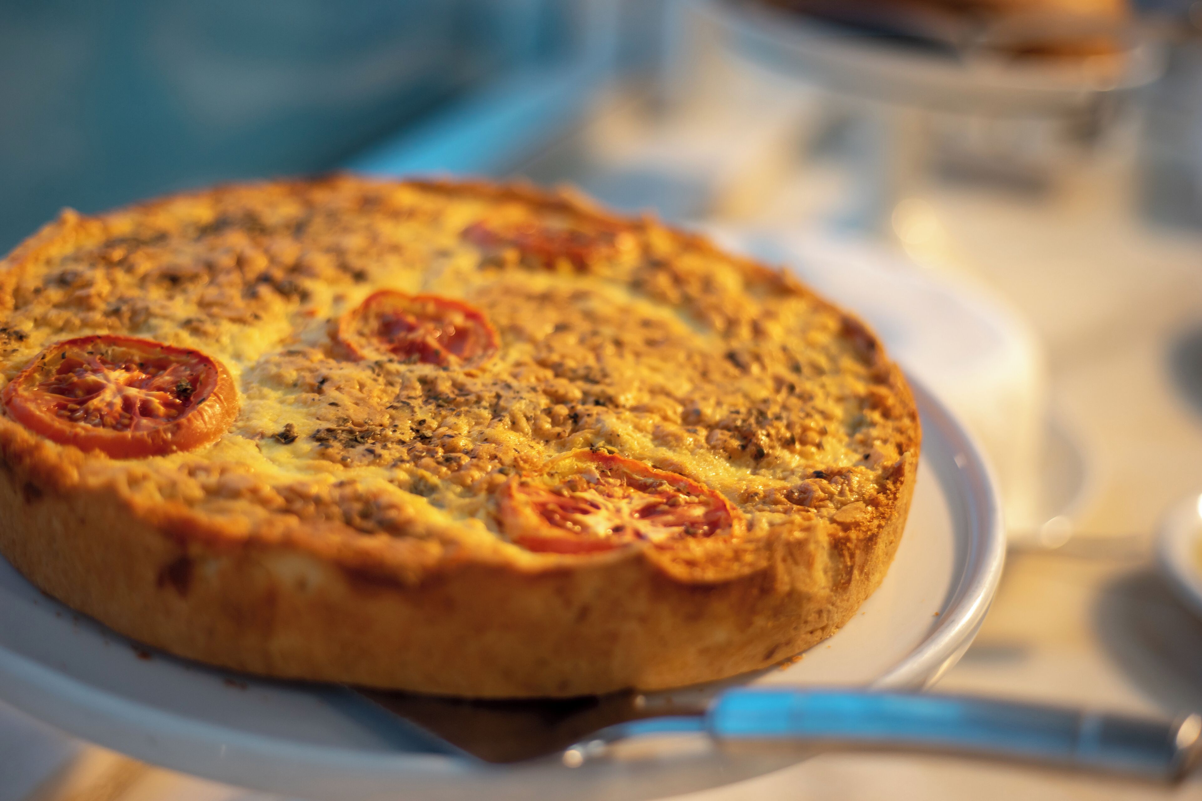 Eine Nahaufnahme einer Pizza mit Tomatenscheiben auf einem weißen Teller.