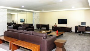 A modern living room with a sectional sofa, wooden coffee table, and a flat-screen TV mounted on the wall.
