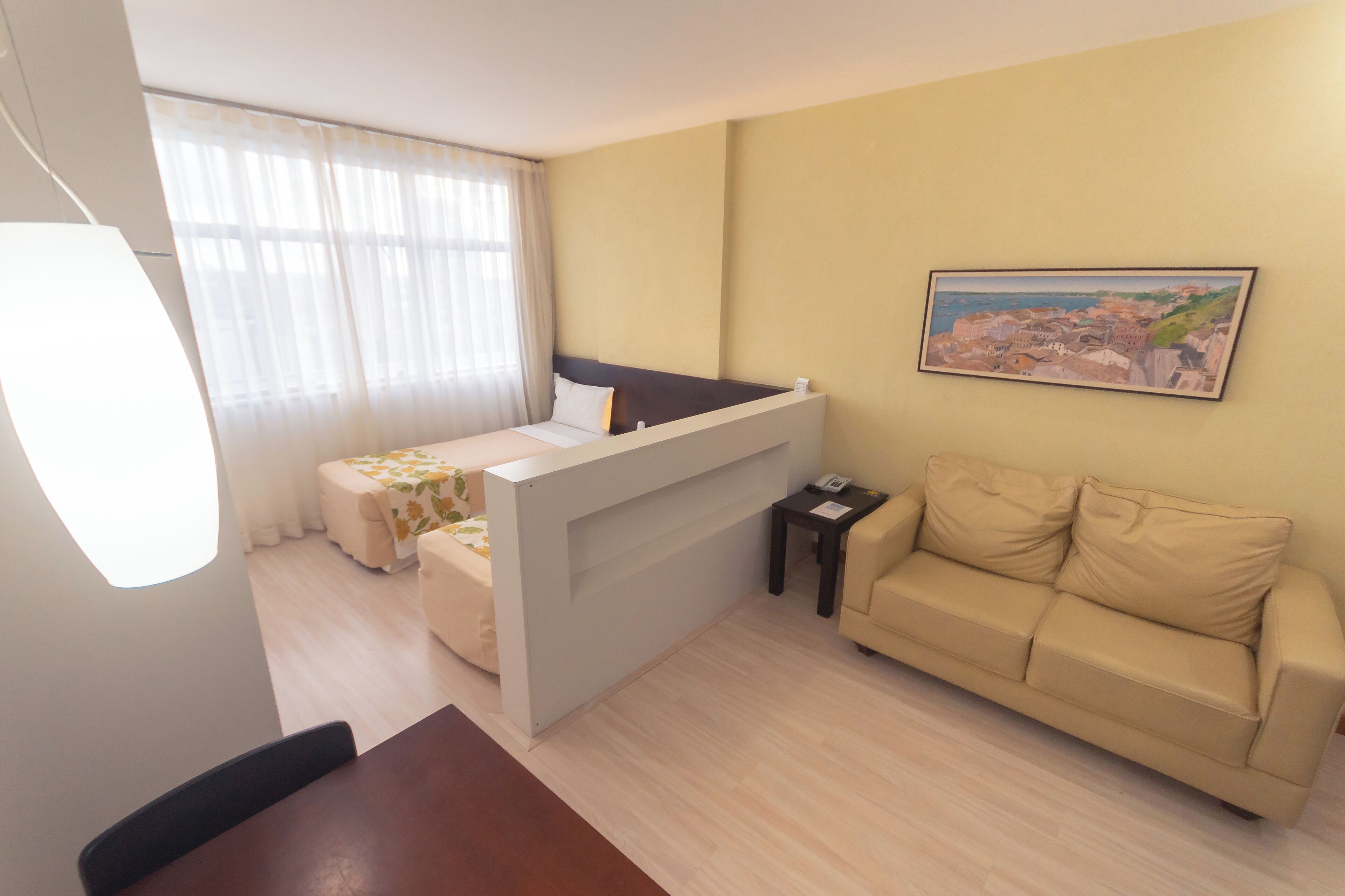 Un espacio habitable compacto con una cama, un sofá, una mesa de comedor y un cuadro en la pared.