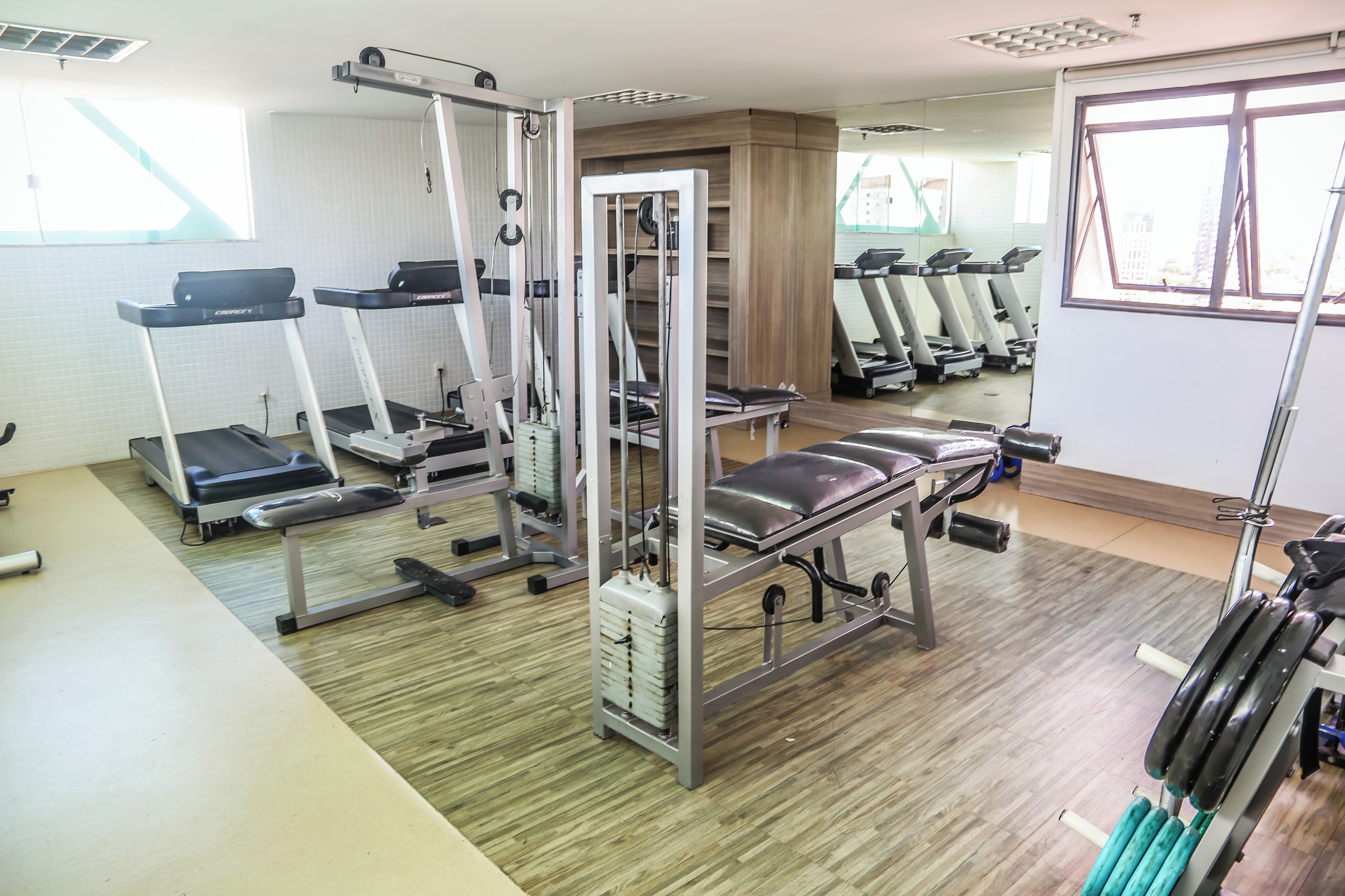 Ein Fitnessstudio mit Laufbändern, Krafttrainingsgeräten und einer Bank.