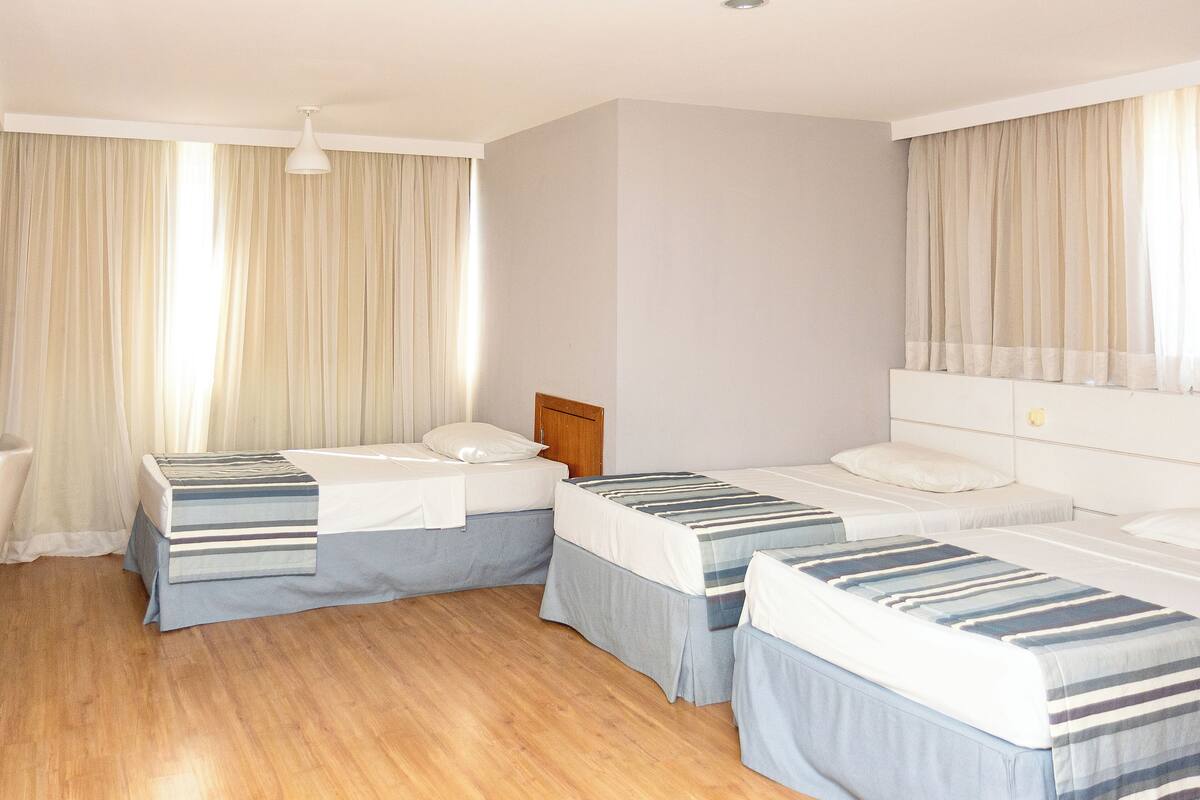 A room with three beds, a wooden floor, and white walls.