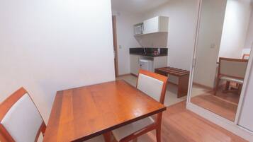 Comedor con mesa y sillas de madera, cocina al fondo y puerta corredera que da a otra habitación.