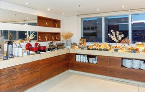 Una barra de desayuno moderna con mostrador de madera, diversas opciones para el desayuno y plantas decorativas.