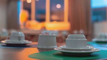A table with white teapots and cups on green placemats.