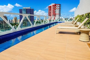 Una piscina al aire libre, sombrillas, sillones reclinables de piscina