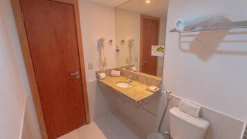 Une salle de bain avec une porte en bois, un lavabo surmonté d’un miroir et un porte-serviettes.