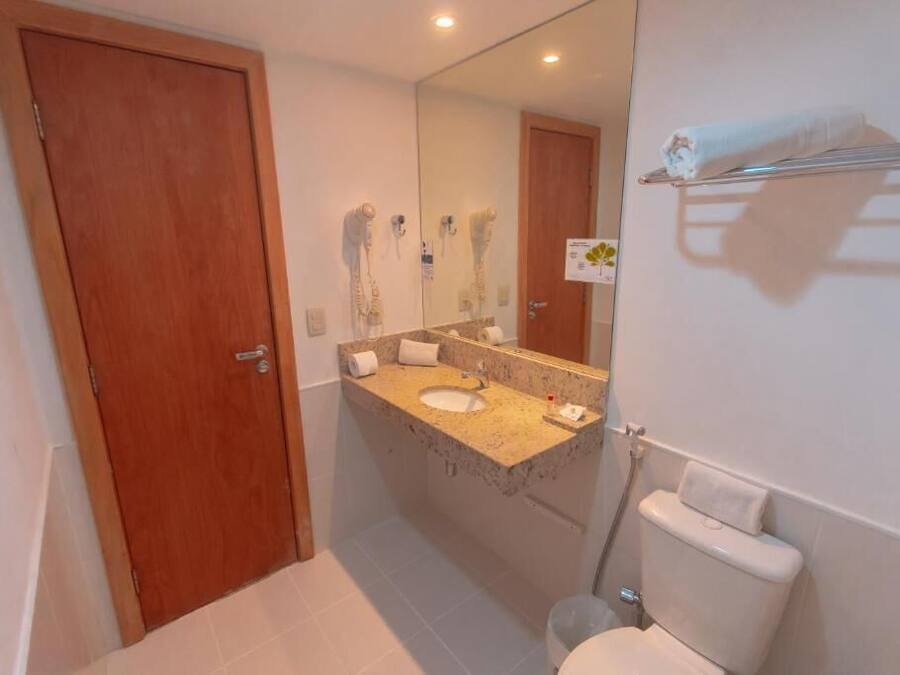 Une salle de bain avec une porte en bois, un lavabo surmonté d’un miroir et un porte-serviettes.