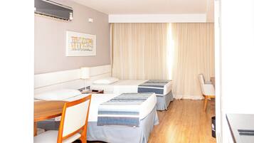 Habitación de hotel con dos camas, un escritorio, una silla, una lámpara y un cuadro en la pared.