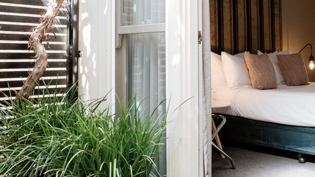 A bedroom with a bed, a window, and a wall-mounted air conditioner. - Alexandra Place (Bendigo)