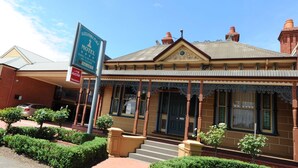 A two-story building with a prominent sign for the Alexandra Place Motel, featuring a classic architectural style with ornate detailing and a tiled roof.