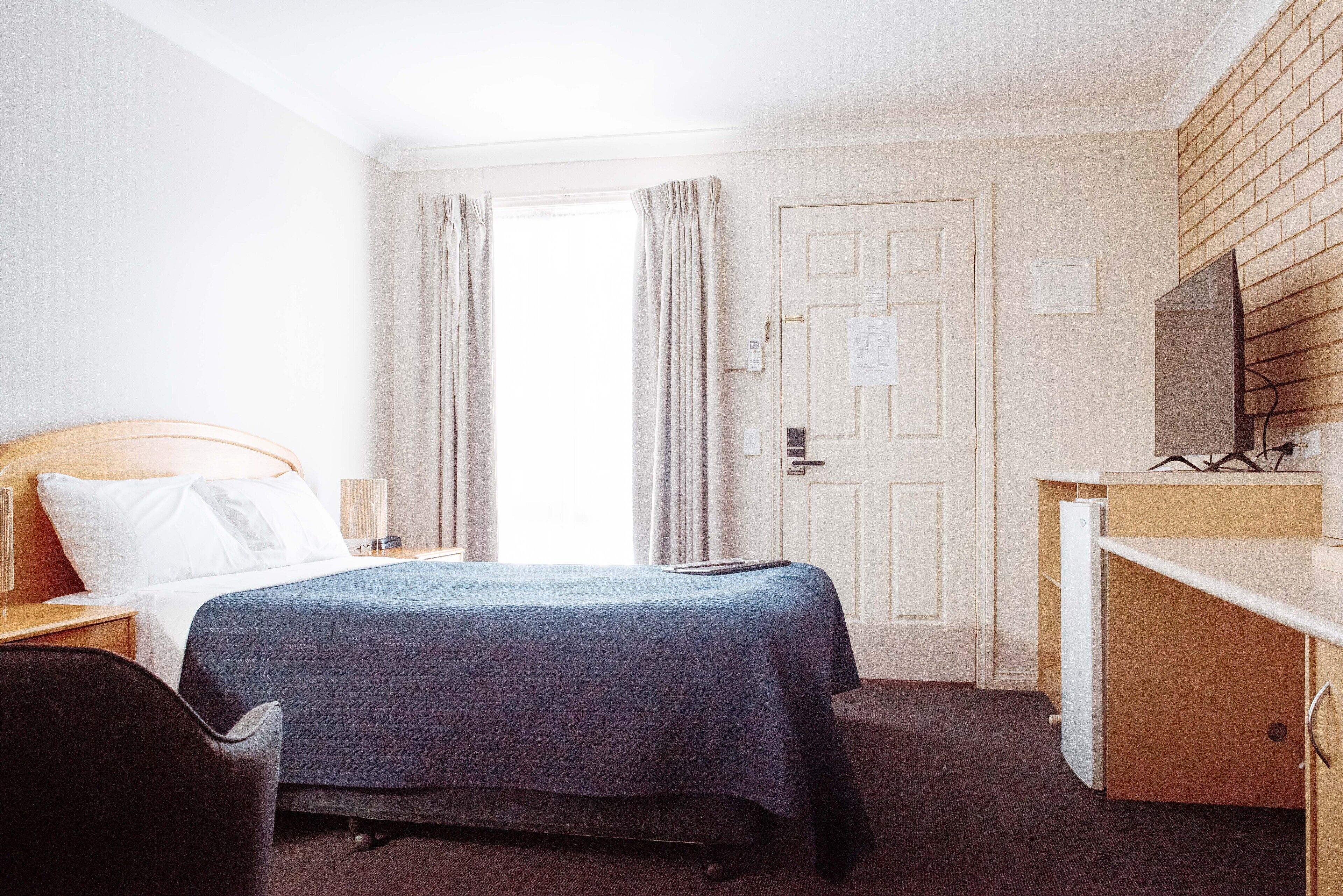 Habitación de hotel con cama, escritorio, silla, televisión y puerta con cerradura y llave en la cerradura.