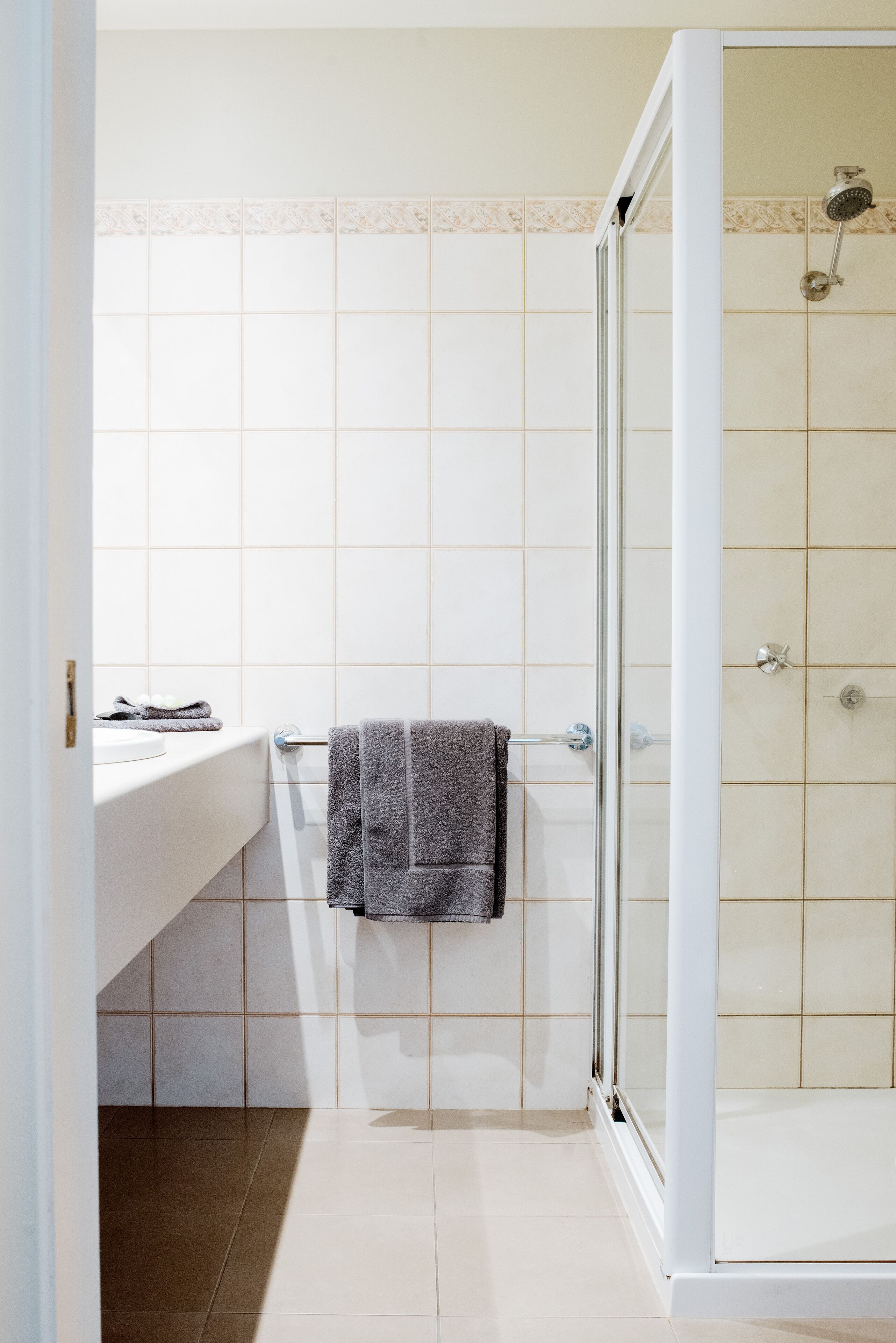 Un bany amb dutxa, un lavabo i un penjador de tovalloles.