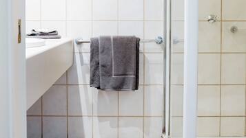 Un bany amb dutxa, un lavabo i un penjador de tovalloles.
