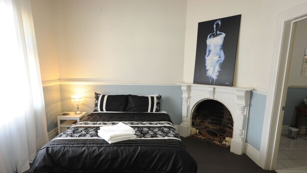 A bedroom with a large bed, a fireplace, and a painting on the wall.
