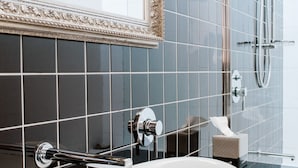A bathroom with a white sink, a mirror with an ornate frame, and a shower area.