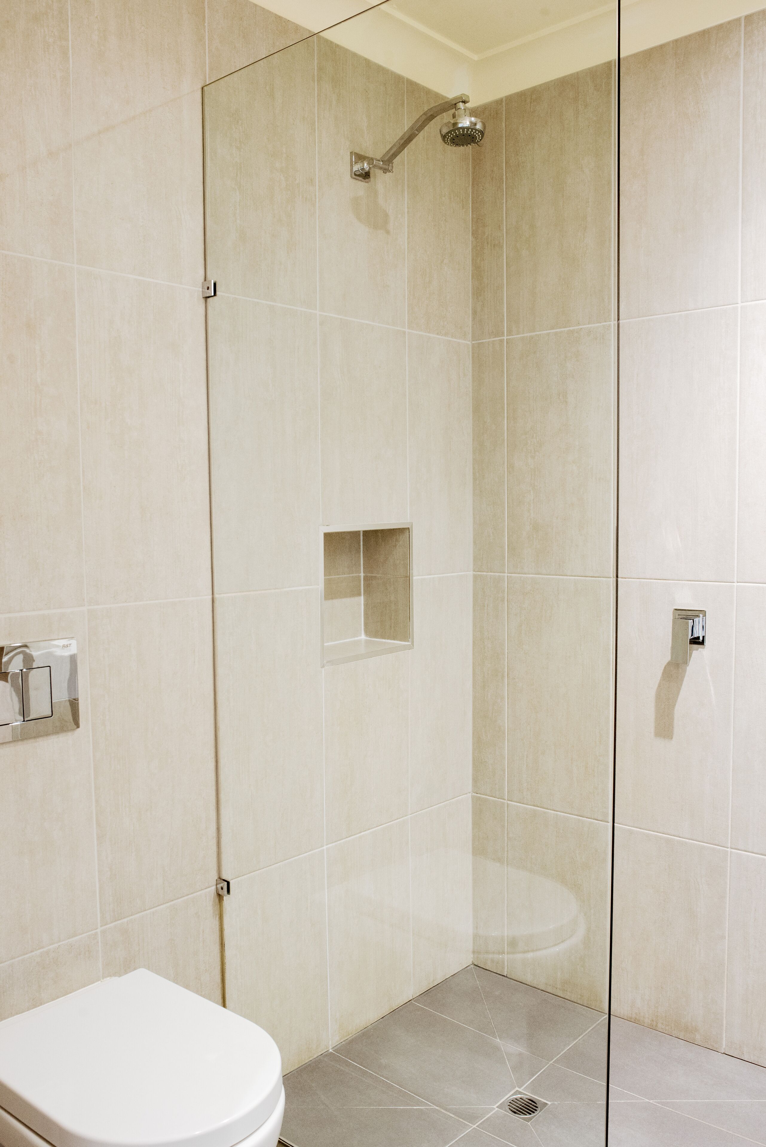 Un baño moderno con cabina de ducha de vidrio, inodoro y lavamanos.