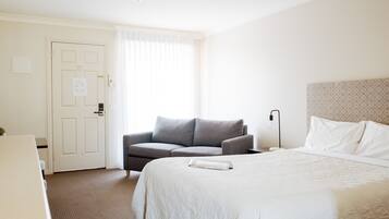 Een hotelkamer met een bed, een slaapbank, een bureau en een deur.