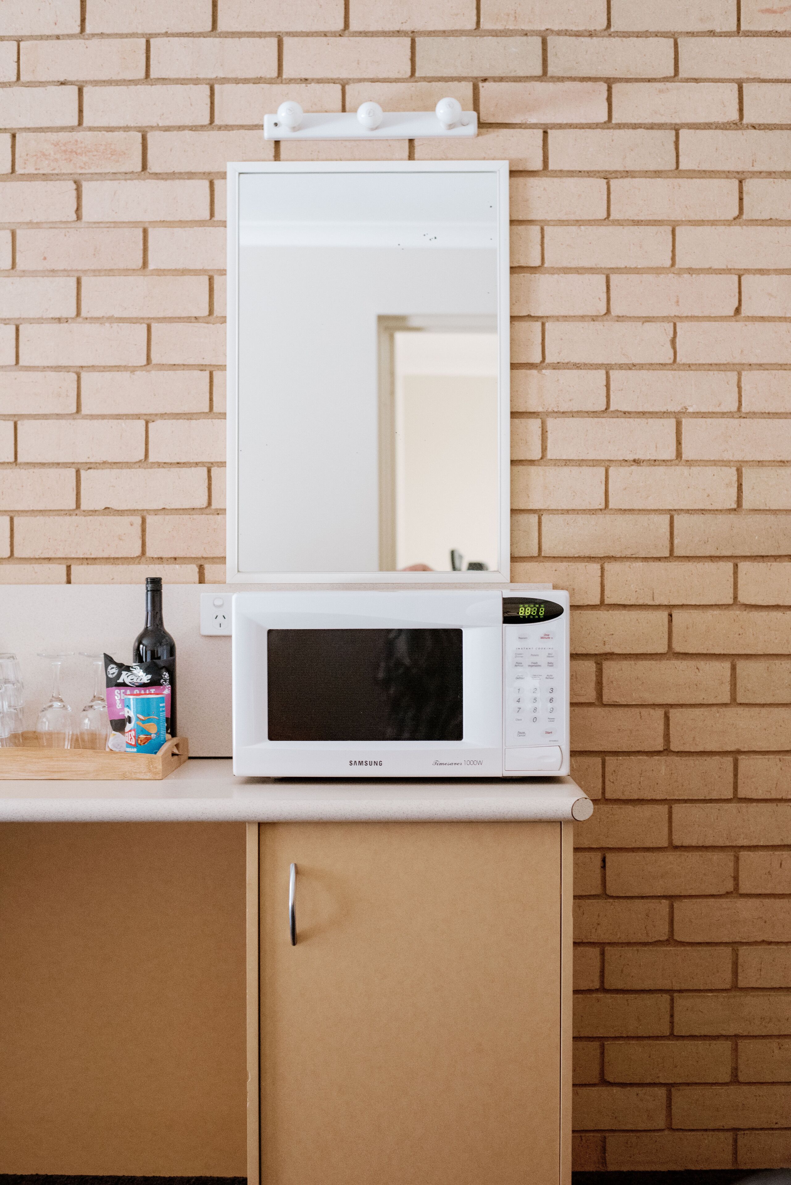 A white microwave oven on a wooden counter with a brick wall background.