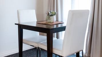 A dining area with a dark wooden table, white chairs, and a small plant on the table.