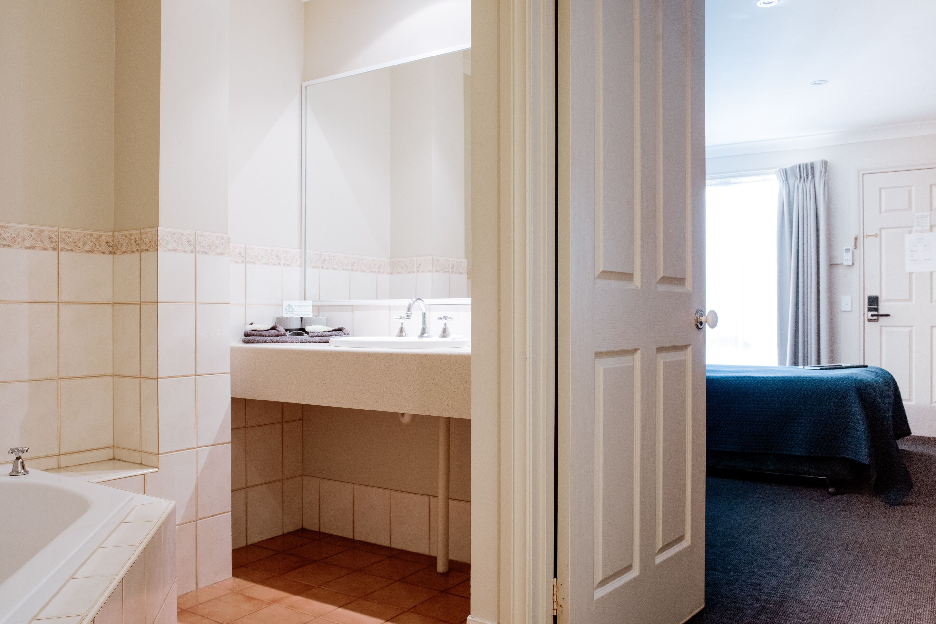 Een hotelbadkamer met een bad, wastafel en spiegel.