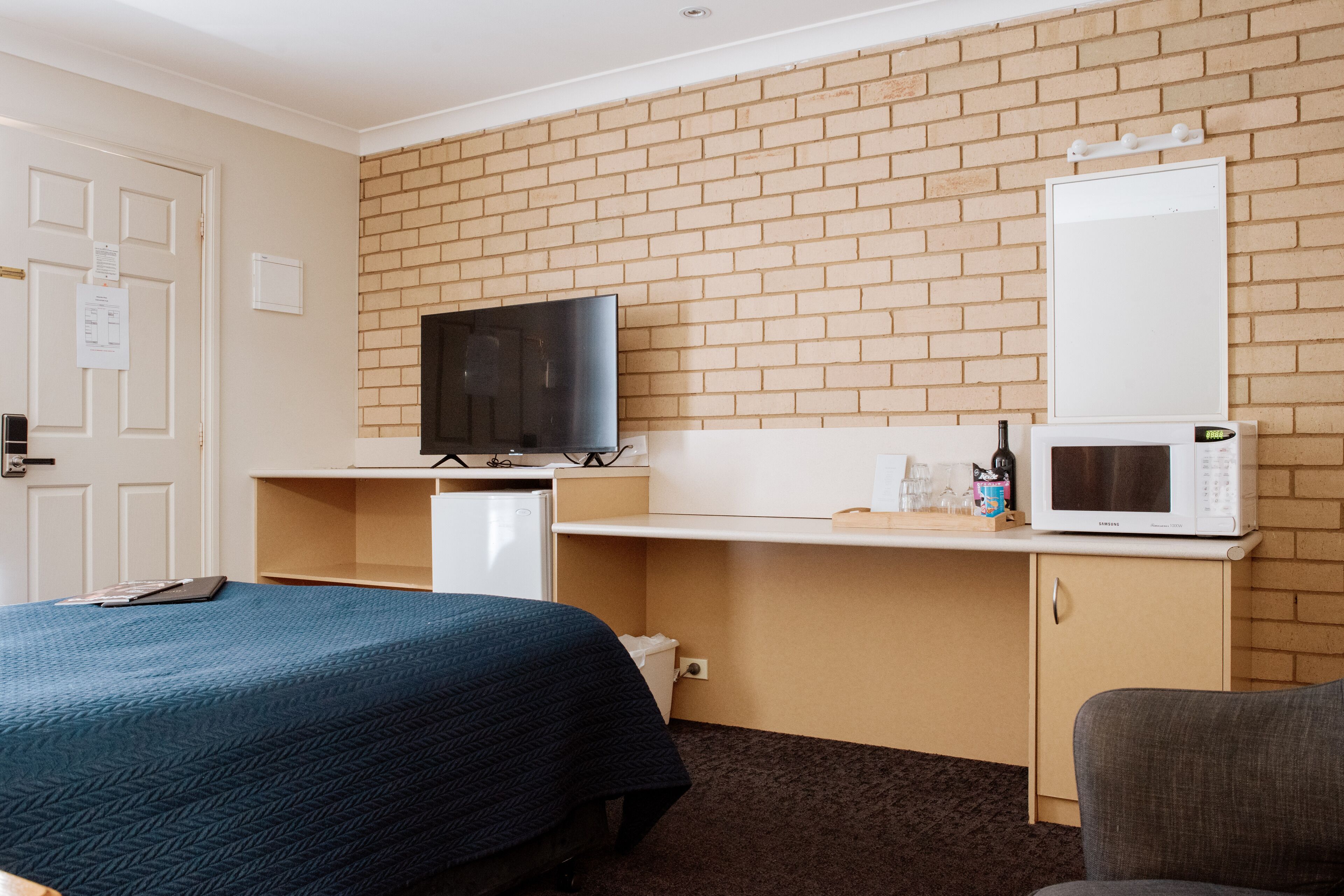 Een hotelkamer met een bed, een televisie, een magnetron en een klein bureau.