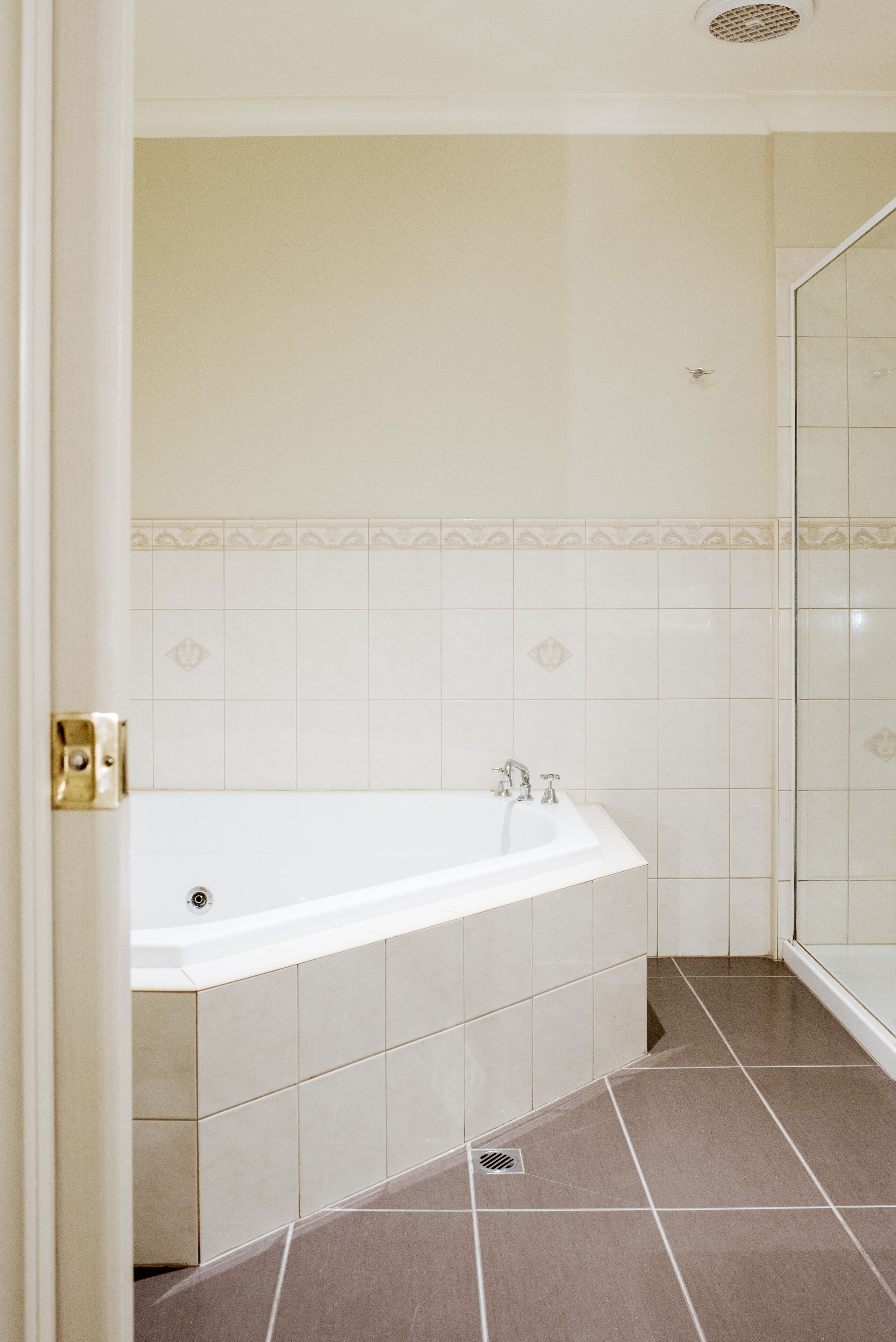 A bathroom with a bathtub, a shower area, and a tiled floor.