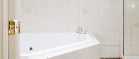 A bathroom with a bathtub, a shower area, and a tiled floor.