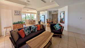 Een moderne woonkamer met een bank, salontafel en eethoek.