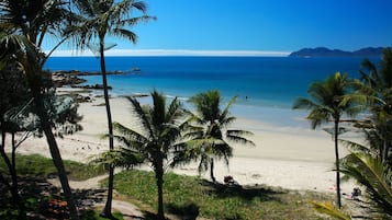 Na praia, espreguiçadeiras, guarda-sóis, toalhas de praia 