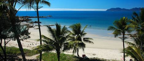 Na praia, espreguiçadeiras, guarda-sóis, toalhas de praia 