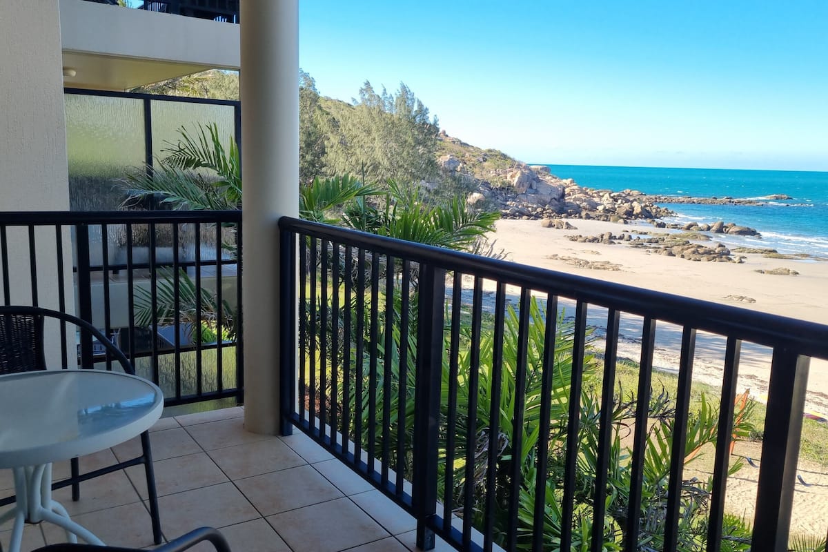 A balcony with a view of a rocky beach and ocean.