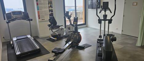 A gym with a treadmill, elliptical, and stationary bike.