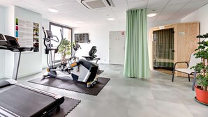 Un gimnasio con cintas de correr, bicicletas estáticas y una máquina de remo.