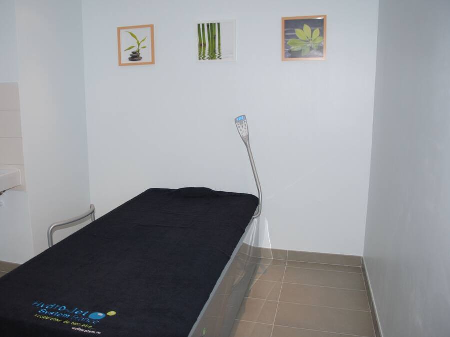 Een kamer met een zwart bed, een stoel en drie ingelijste foto's aan de muur.