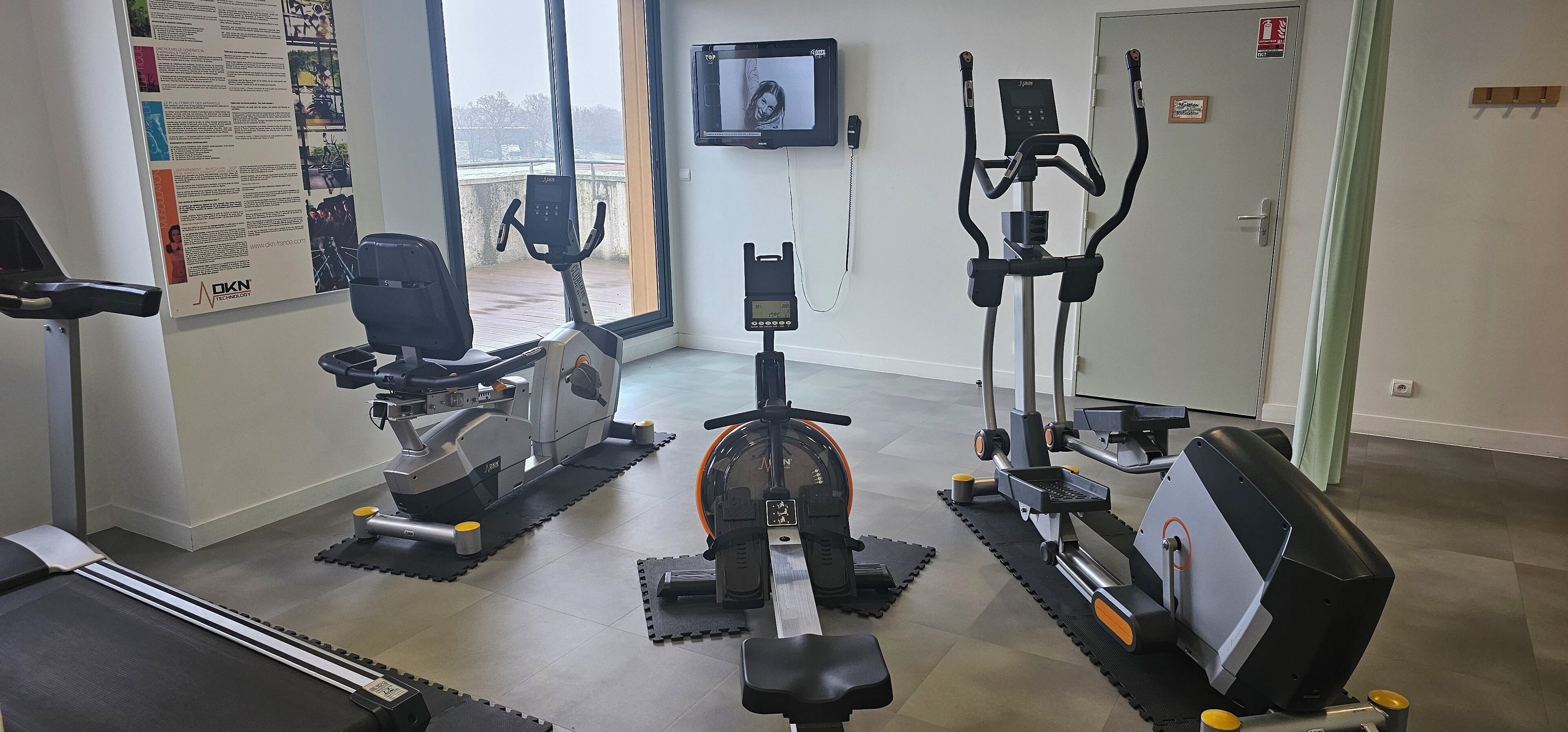 Un gimnasio con máquinas de cardio, una cinta de correr y una bicicleta estática.