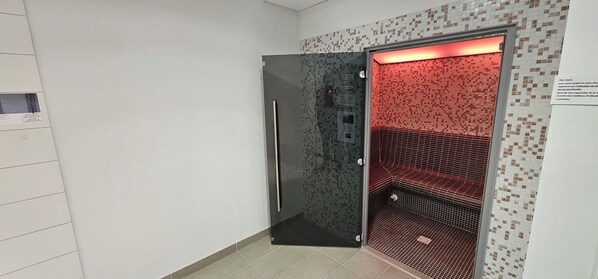 A modern elevator with a metallic door and a red-lit interior.
