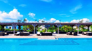 A pool area with lounge chairs and a covered seating area.
