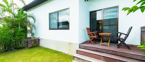 A house with a porch, two wooden chairs, and a table.