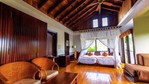 A spacious room with a high ceiling, wooden beams, a bed with a canopy, wicker furniture, and a wooden floor. - LiVEMAX AMMS CanNa Resort Villa (Ginoza)