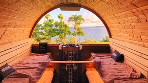 A cozy cabin with a wooden interior, a bench, and a view of the sea and trees. - LiVEMAX AMMS CanNa Resort Villa (Ginoza)