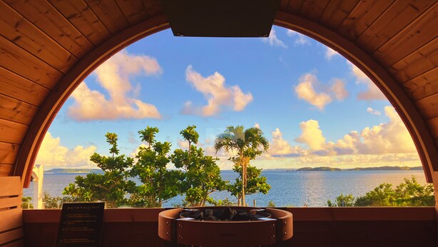 A wooden room with a large arched window overlooking a body of water and trees. - LiVEMAX AMMS CanNa Resort Villa (Ginoza)