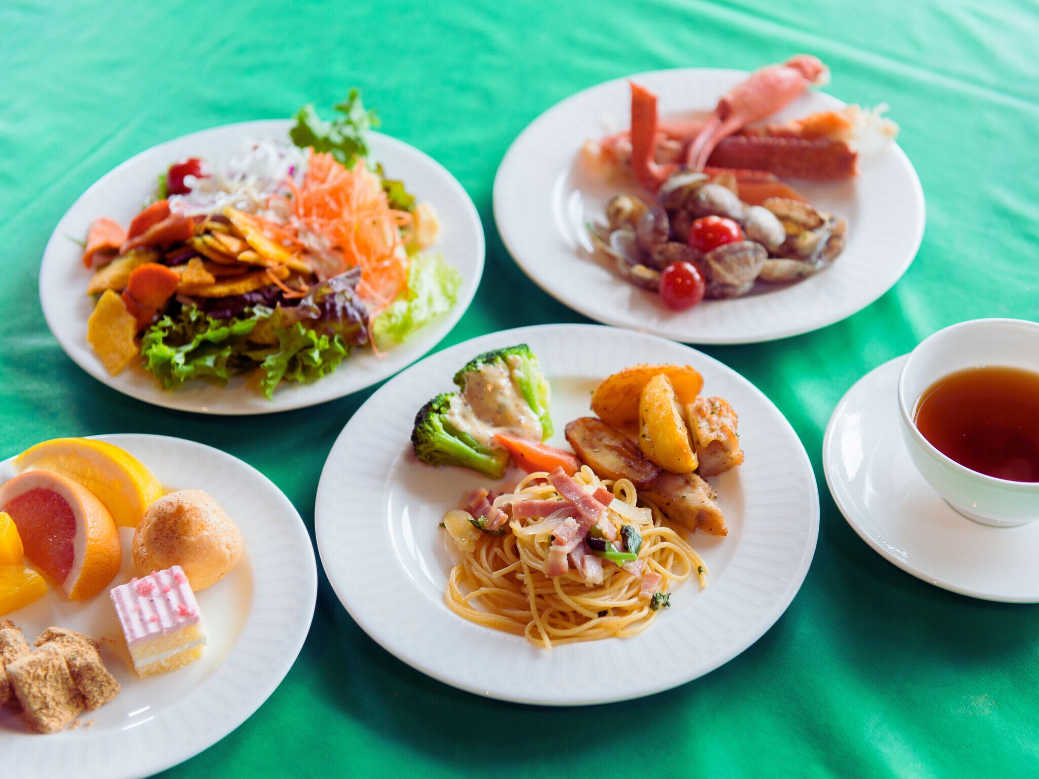 A table with various dishes including pasta, salad, and seafood, along with a cup of tea.