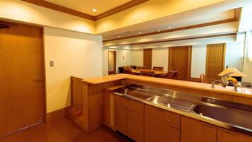 A modern kitchen with wooden cabinets, a stainless steel sink, and a dining area with chairs.