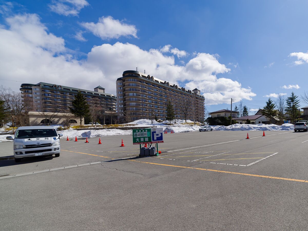 A parking lot with a sign indicating a parking area and a building in the background.