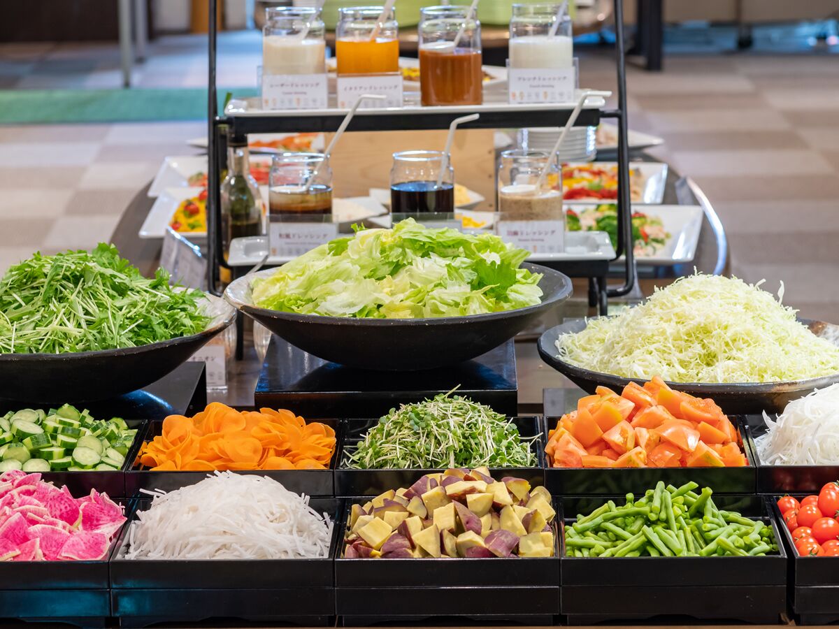 A buffet with various food options including fresh vegetables, salads, and a selection of beverages.