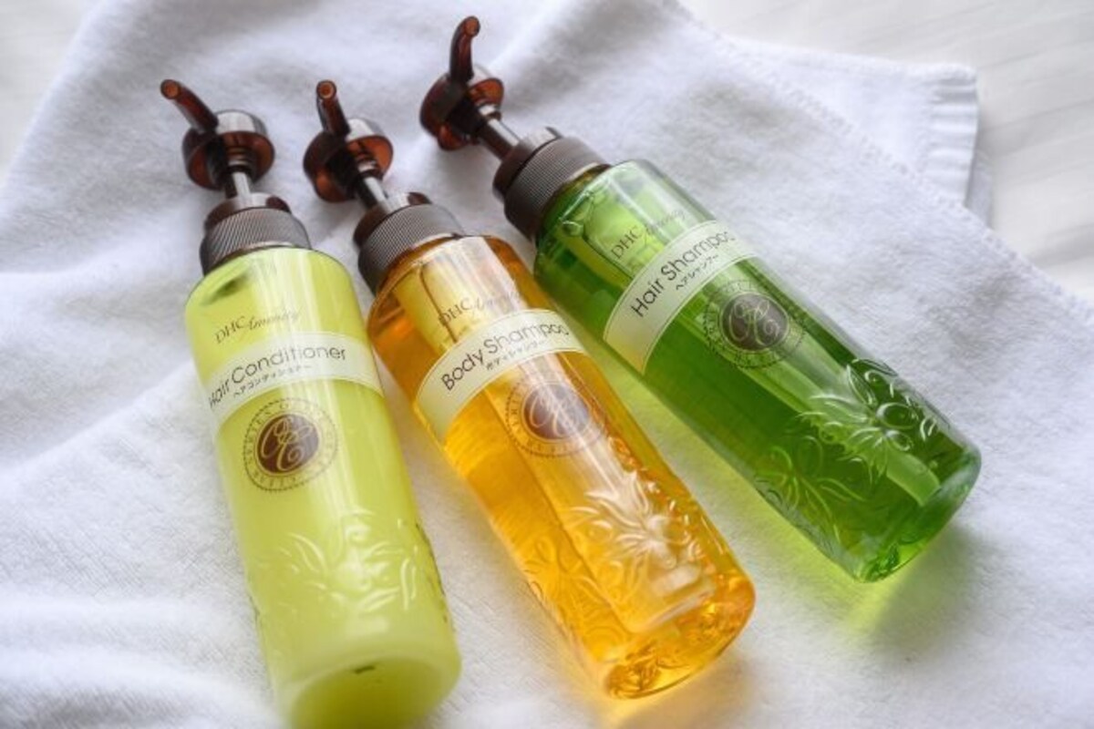 Tres botellas de acondicionador para el cabello sobre una toalla blanca.